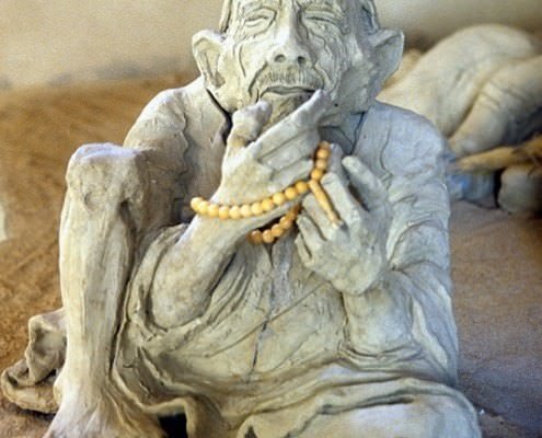 Clay sculpture of an old man sitting