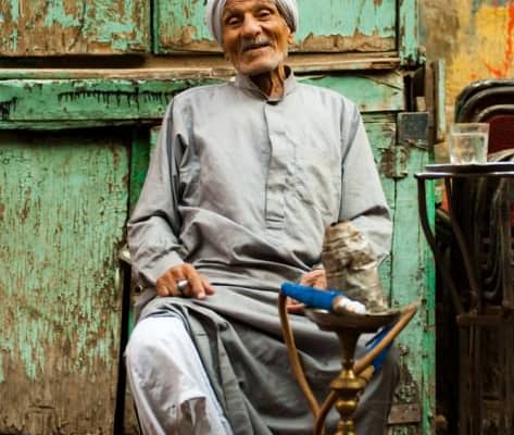 Old Egyptian man sits at a street cafe smoking sheesha in Islamic Cairo