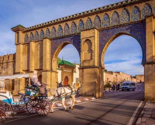 Private Guided Tours of Morocco - Tourist coach crosses Bab Moulay Ismail in front of the famous mausoleum in Meknes, Morocco