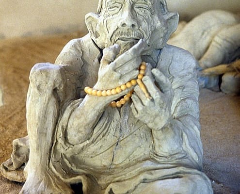Clay sculpture of an old man sitting
