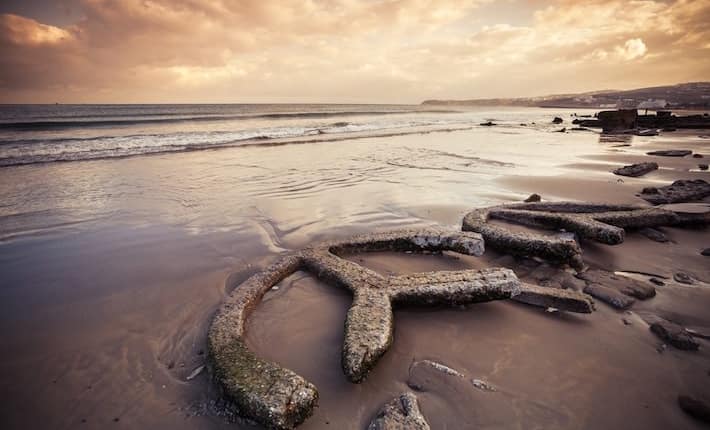 Atlantic ocean coast, old broken concrete construction lays on wet sand , Tangier, Morocco