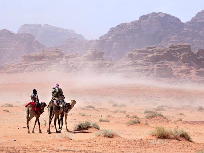 People on camels going through the desert