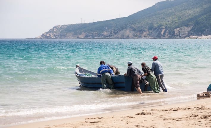 Tangier Morocco Attractions - Unidentified men pull a fishing boat to the beach.