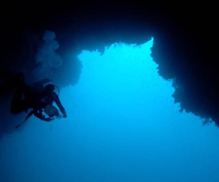 Technical diver passing under the Arch of the Blue Hole in Dahab