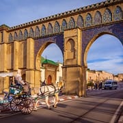 Private Guided Tours of Morocco - Tourist coach crosses Bab Moulay Ismail in front of the famous mausoleum in Meknes, Morocco