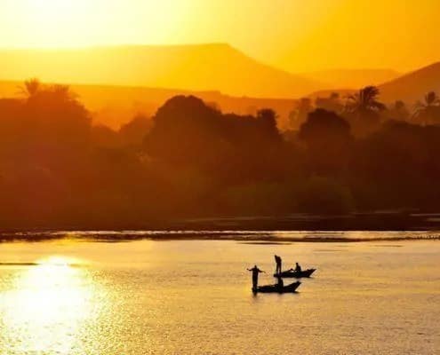 Silhouettes of fishermen on traditional boats at sunset
