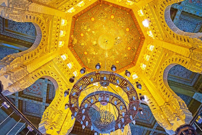 The scenic cupola of Abu al-Abbas al-Mursi Mosque with stone arches from the sides and carved wooden decor in the middle.